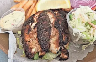  ?? WADE TATANGELO/SARASOTA HERALD-TRIBUNE ?? A blackened grouper sandwich at Tide Tables Restaurant and Marina