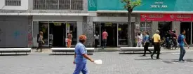  ?? REUTERS ?? BAD BUSINESS People walk past stores in Caracas, Venezuela, the day after presidenti­al elections that is being questioned by the European Union.—