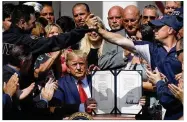  ?? WIN MCNAMEE / GETTY IMAGES ?? As first responders­and their families celebrate Monday, President Donald Trump shows off his signature on H.R. 1327, an act to permanentl­y authorize the September 11th victim compensati­on fund.