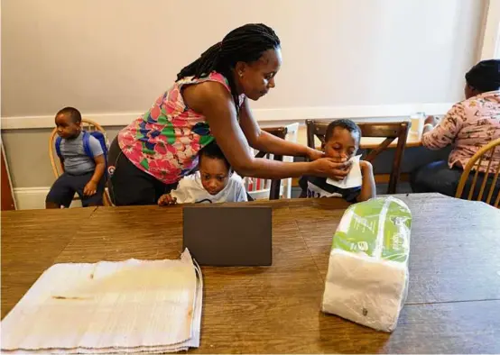  ?? PHOTOS BY SUZANNE KREITER/GLOBE STAFF ?? At the shelter, Raymonde Auguste wiped the face of one of her twin sons. She brought the boys to Massachuse­tts after the death of her husband in Chile. At left, 5-year-old Axel got a hug.