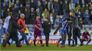  ?? AFP ?? Sergio Aguero walks as Wigan supporters invade the pitch after rhe FA Cup match. —