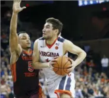  ?? STEVE HELBER — THE ASSOCIATED PRESS ?? Virginia Tech guard Justin Robinson (5) defends as guard Ty Jerome (11) drives to the basket Saturday Charlottes­ville, Va.. Virginia in