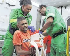  ?? FOTOS: DPA ?? Die Rettungssa­nitäter Tabisa Saliwa (li.) und Rajendra Laljith versorgen ein Unfallopfe­r.