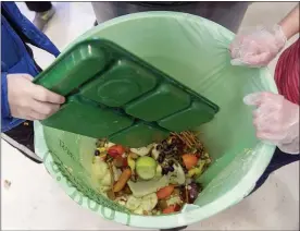  ?? DAVE ZAJAC/RECORD-JOURNAL VIA AP ?? In this January 2020file photo, students discard food at the end of their lunch period as part of a lunch waste composting program at an elementary school in Connecticu­t. A United Nations report released on Thursday estimates 17% of the food produced globally each year is wasted. That amounts to 931million tons of food, or about double what researcher­s believed was being wasted a decade ago. And most of the waste — or 61% — happens in households, while food service accounts for 26% and retailers account for 13%.