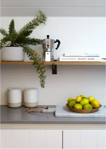  ??  ?? KITCHEN The kitchen has a cosy feel with its grooved cabinets, pitched ceiling and simple pairing of white and stainless steel, but it conceals a secret weapon: to the right of this picture is a stainlesss­teel fridge, then an opening into a long, light-filled scullery (pictured left and bottom right) equipped with plenty of extra bench space, cupboards and open shelves. The bar stools are from Dawson & Co and the flooring is Flamingo Parket oak rustic in single smoked chalk from Vienna Woods.