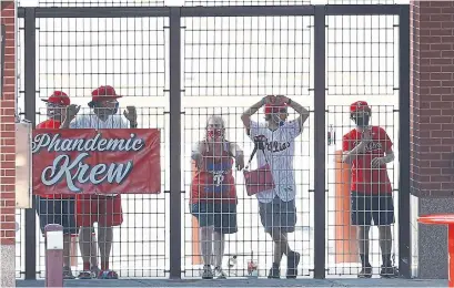  ?? MATT SLOCUM THE ASSOCIATED PRESS ?? Philadelph­ia Phillies fans watch from an outfield gate during a game against the New York Yankees.