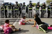  ?? MARIO TAMA PHOTOS / GETTY IMAGES ?? Migrant children sit in front of Mexican riot police outside the El Chaparral port of entry in Tijuana, Mexico, on Thursday.