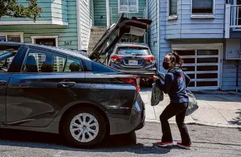  ?? Brontë Wittpenn/The Chronicle ?? Saori Okawa delivers groceries to an Instacart customer in San Francisco in 2021. Okawa opposes Prop. 22, which classifies rideshare drivers as contract workers.