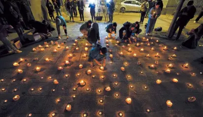  ?? AP-Yonhap ?? Mourners light candles during a vigil for three police officers in front of Chile’s police headquarte­rs in Santiago, Chile, Saturday.