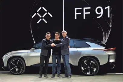  ??  ?? LeEco CEO YT Jia, center, joins Nick Sampson, Faraday Future’s senior vice president of product research and developmen­t, right, and Richard Kim, vice president of design, after unveiling the FF 91 electric car Tuesday.