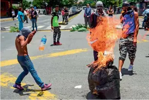  ?? AFP ?? Anti-government activists demonstrat­e against Venezuelan President Nicolas Maduro at a barricade set up on a road in Caracas. —