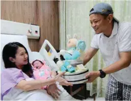  ??  ?? Lee Chee Hong, 36, presenting a gift to his wife Yew Hong Khim, 28, after she gave birth to a baby girl weighing 3.07kg on Mother's Day at Island Hospital in George Town, Penang.