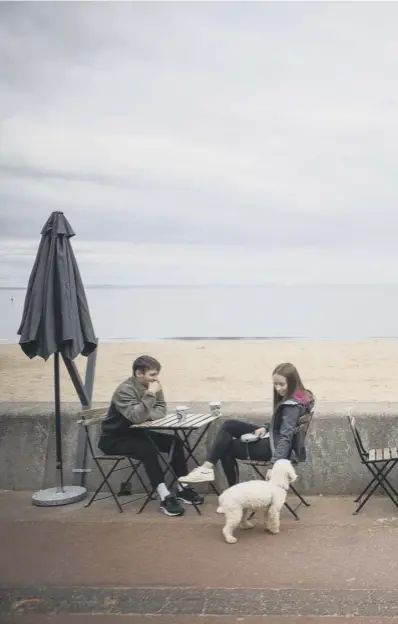  ??  ?? 0 People drank coffee on the promenade at Edinburgh’s Portobello Beach underneath overcast skies at the start of a week in which the UK is expected to bask in temperatur­es of more than 30C