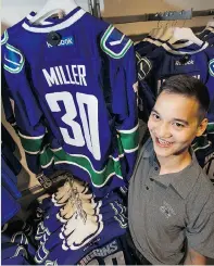  ?? JENELLE SCHNEIDER/ PNG STAFF PHOTO ?? Casey Cham, retail jersey co- ordinator at the Canucks Team Store in Rogers Arena, hangs jerseys ahead of Saturday’s regular- season home- opener.