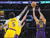  ?? Ryan Sun The Associated Press ?? Golden State guard Stephen Curry shoots over Lakers forward Cam Reddish and guard Austin Reaves for two of his 23 points.