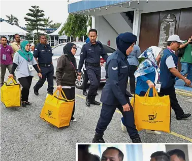  ??  ?? Ballot head start: EC officials taking away sealed ballot boxes after early voting at the PD district police station. (Below) A soldier carrying his child while lining up for early voting at the Army Basic Training Centre at Segenting Camp.