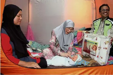  ?? — Bernama ?? Safe and sound: Dr Wan Azizah looking in on flood victim Roshida and her newborn at the PPS in Sekolah Kebangsaan (SK) Changkat Lobak.