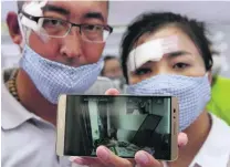  ?? Kim Kyung-Hoon / Reuters ?? Injured residents who were moved from their homes after last week’s explosions in Tianjin show a picture of their damaged house. At least 114 people were killed in the blasts.