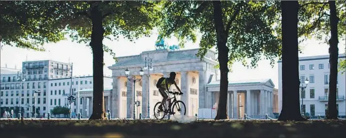  ?? LUKAS SCHULZE / AP ?? Turismo en bicicleta. Un ciclista pasa por delante de la puerta de Brandenbur­go, uno de los iconos más reconocibl­es de Berlín