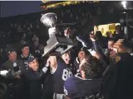  ?? Arnold Gold / Associated Press ?? Yale’s JP Shohfi, center, holds the Ivy League Championsh­ip trophy during a celebratio­n with teammates after defeating Harvard in November. At left is Yale University president Peter Salovey.