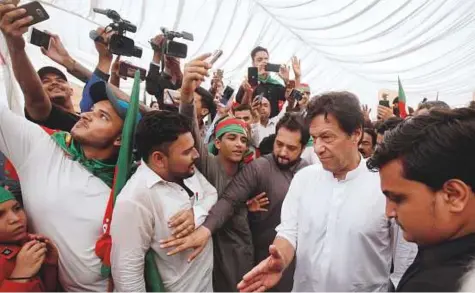  ?? Reuters ?? Chairman of the PTI party Imran Khan (second right) gestures to clear the way among supporters during a campaign meeting ahead of general elections in Karachi, yesterday.