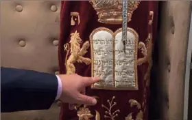  ?? Jon Gambrell/Associated Press ?? Alex Peterfreun­d, a co-founder of Dubai’s Jewish community and its cantor, points toward a cover on a Torah scroll bearing the Ten Commandmen­ts, in Dubai, United Arab Emirates, on Sunday.