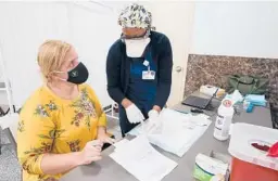  ?? MARY ALTAFFER/AP ?? A nurse goes over paperwork with mosque member Zejreme Rodoncic after giving her the COVID-19 vaccine Thursday in the Staten Island borough of New York.