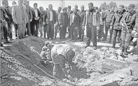  ?? Adel Hana Associated Press ?? IN BEIT HANOUN in the Gaza Strip, security personnel inspect the site of the explosion that slightly injured five people in the last vehicle of a convoy carrying Palestinia­n Authority Prime Minister Rami Hamdallah and intelligen­ce chief Majid Faraj,...