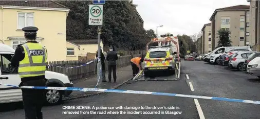  ??  ?? CRIME SCENE: A police car with damage to the driver’s side is removed from the road where the incident occurred in Glasgow