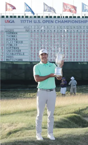  ?? DAVID J. PHILLIP/THE ASSOCIATED PRESS ?? Brooks Koepka holds up the U.S. Open winner’s trophy at Erin Hills Golf Club in Erin, Wis., a stunning golf course that demands all sorts of shotmaking.