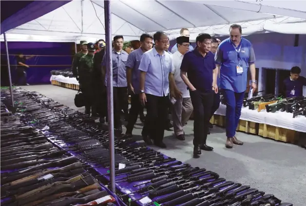  ?? Malacañang photo
Malacañang photo ?? Left, the President of the Philippine­s Rodrigo Duterte inspects the decommissi­oned firearms from former combatants of the Moro Islamic Liberation Front, or the MILF, at the Old Provincial Capitol Compound in Sultan Kudarat, Maguindana­o. Below, Duterte salutes and greets former members of the MILF at their passing out ceremony.