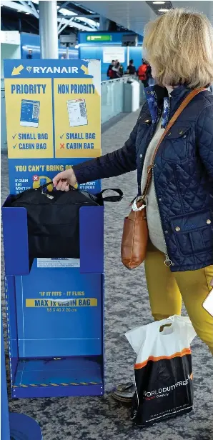  ??  ?? Tight fit: A passenger checks the size of her cabin bag at the airport