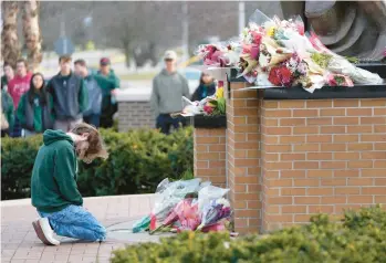  ?? PAUL SANCYA/AP ?? A student kneels in front of a makeshift memorial Tuesday on the Michigan State campus in East Lansing.