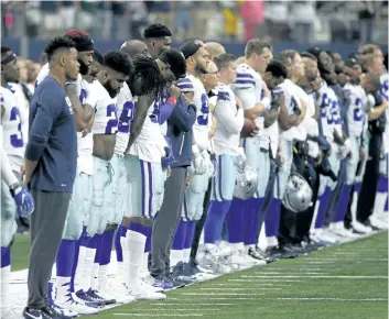  ?? RON JENKINS/THE ASSOCIATED PRESS ?? Dallas Cowboys players and staff stand on the sideline during the playing of the national anthem before Sunday’s game against the Green Bay Packers in Arlington, Texas.
