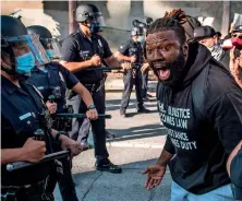  ?? — AFP ?? Burning Anger: A demonstrat­or confronts police as he protests the death of george Floyd in Los Angeles.