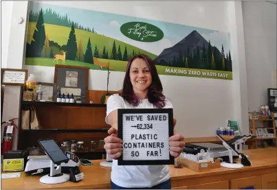  ?? PHOTOS BY JOSE CARLOS FAJARDO — STAFF PHOTOGRAPH­ER ?? Byrd's Filling Station owner Laura Porter holds a sign she displays in the front window in San Mateo. Porter estimates she has saved over 62,000plastic containers since 2019at her grocery business that specialize­s in sustainabi­lity, organic foods and zero waste.