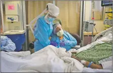  ?? (File Photo/AP/Jae C. Hong) ?? Romelia Navarro (right) is comforted by nurse Michele Younkin (left) as she weeps while sitting at the bedside of her dying husband, Antonio Navarro, in St. Jude Medical Center’s covid-19 unit in Fullerton, Calif., on July 31.