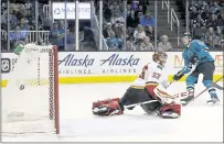  ??  ?? Justin Braun of the Sharks gets the puck past Calgary goaltender David Rittich during the third period Saturday at SAP Center.