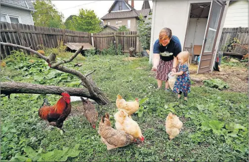  ?? [CHARLIE NEIBERGALL/THE ASSOCIATED PRESS] ?? Tanya Keith, of Des Moines, Iowa, and her daughter Iolana feed chickens in the backyard of their home. The trend of raising backyard chickens is causing a soaring number of illnesses from poultry-related diseases. Keith said the nine hens and a rooster...