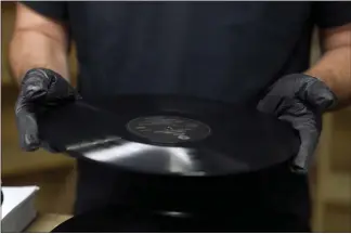  ?? ?? Ricky Riehl inspects finished vinyl records for physical flaws before they are packaged at the United Record Pressing facility Thursday in Nashville, Tenn.