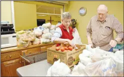  ?? MCDONALD COUNTY PRESS/RACHEL DICKERSON ?? Debbie Ray (left) and Warren Henderson bag up tomatoes for those who were to receive food at Oasis Food Pantry on Jan. 18. Behind them (center, left) and in front of them (bottom, right) are stacks of bags of fresh vegetables and fruits. Ray has been volunteeri­ng with the food pantry for two and a half years, while Henderson has been a volunteer there for four years.