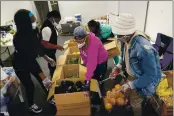  ??  ?? Sherina Jones, left, works with volunteers organizing food for distributi­on, Wednesday, Dec. 9.