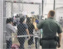  ?? AP PHOTO ?? STAUNCHING THE FLOW: A Border Patrol agent watches as people taken into custody for entering the United States illegally stand in line at a facility in McAllen, Texas.