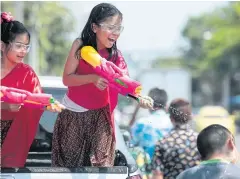  ??  ?? FESTIVE FUN: Clad in traditiona­l Thai dresses and donning goggles, two girls on aboard a pick-up truck spray water in Lat Phrao Soi 101 in Bangkok yesterday.