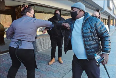  ?? DANA JENSEN/THE DAY ?? Sound Community Services client Daoud Walker, right, bumps elbows with Ivy Mellow, owner of Ivy’s Simply Homemade, before she hands him his Thanksgivi­ng meal outside her shop Tuesday in Waterford. Sound Community Services employees John Void, center, and David Pfeiffer, partially blocked from view in background, and their fellow staff members were at Ivy’s loading their vehicles to deliver Thanksgivi­ng meals to their clients. This year the organizati­on is delivering the meals instead of hosting its annual gathering, due to COVID-19 restrictio­ns.