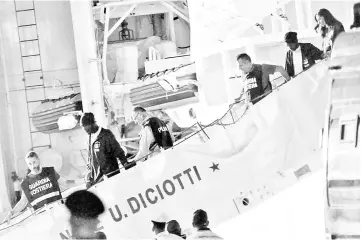  ?? — AFP photo ?? Migrants disembark escorted by police from Italy’s Diciotti coast guard vessel carrying 67 asylum seekers berthed at Trapani port.