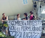  ??  ?? Altri anarchici si sono presentati con striscioni di sostegno. A destra i genitori e la polizia provano a far scendere i ragazzi dal tetto