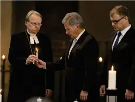  ?? FOTO: LEHTIKUVA / RONI LEHTI ?? President Sauli Niinistö och statsminis­ter Juha Sipilä tänder ljus till minnet av offren från inbördeskr­iget. Ärkebiskop Kari Mäkinen assisterar.