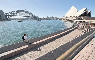  ?? AFP ?? A lone tourist takes photos in Circular Quay in Sydney yesterday, a day after Australia sealed its borders by banning entry for non-residents in order to stem the spread of Covid-19.