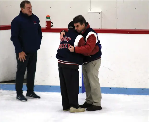  ?? Louriann MArdo-Zayat / lmzartwork­s.com ?? With assistant coach Larry O’Donnell waiting stage left, Mount Saint Charles co-coaches, the father-son duo of Bill and Dave Belisle, share one last on-ice embrace after Saturday night’s 2-1 overtime defeat at the hands of La Salle. The loss knocked the Mounties from the postseason and was the last high school hockey game behind the bench for Bill, 89, and Dave, 59, who announced they were stepping down at season’s end.